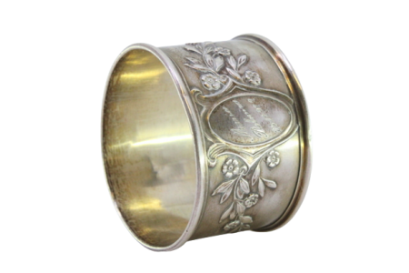 Argola de guardanapo em prata com motivos florais relevados envolvendo cartela para monograma.